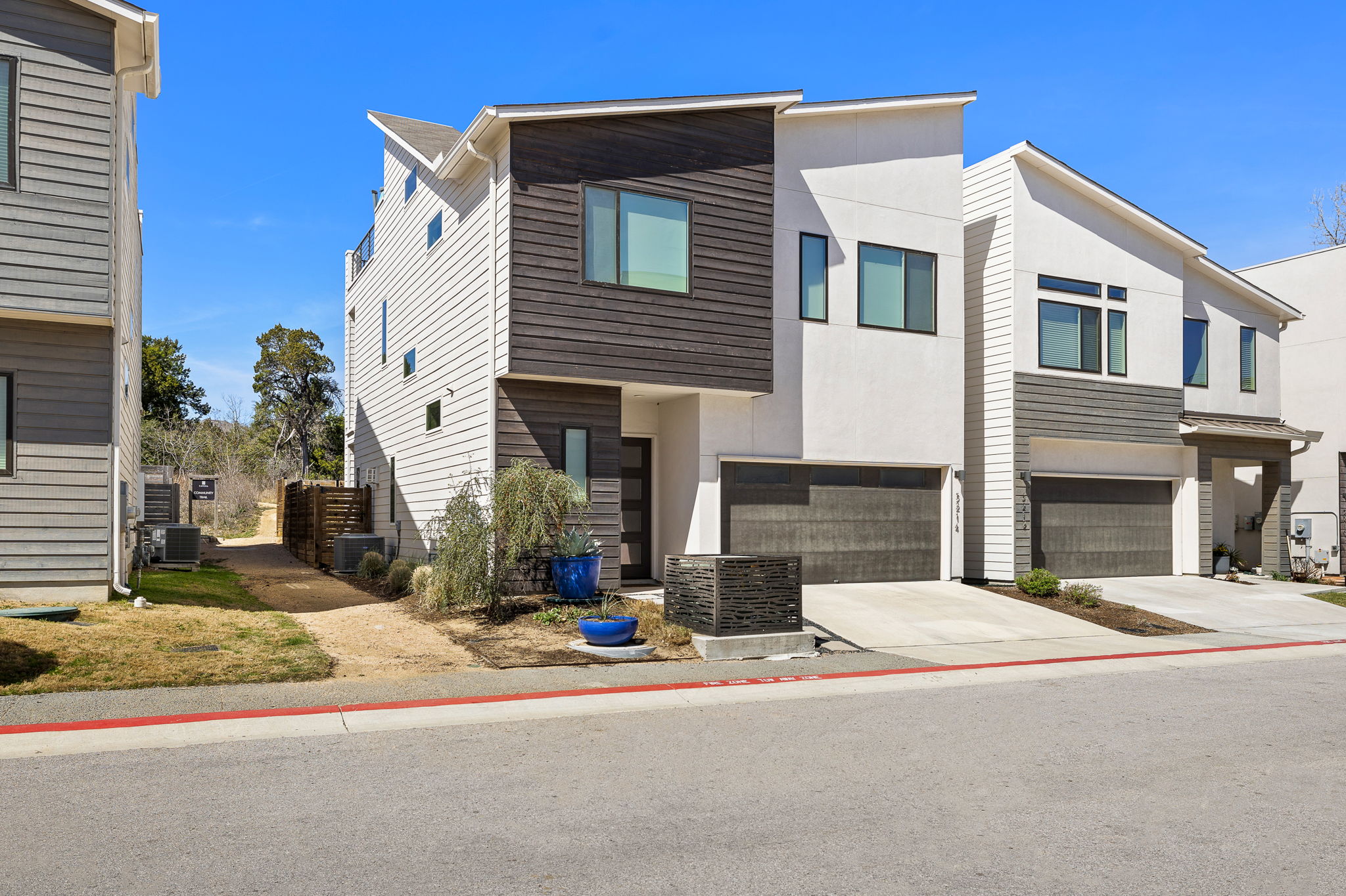 5214 Pink Poppy Pass Austin, TX 78735 - Photo 5 of 34 Modern home with an attached garage, concrete driveway, and stucco siding
