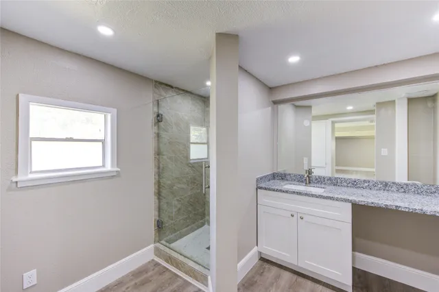 a bathroom with a granite countertop sink a mirror and a shower