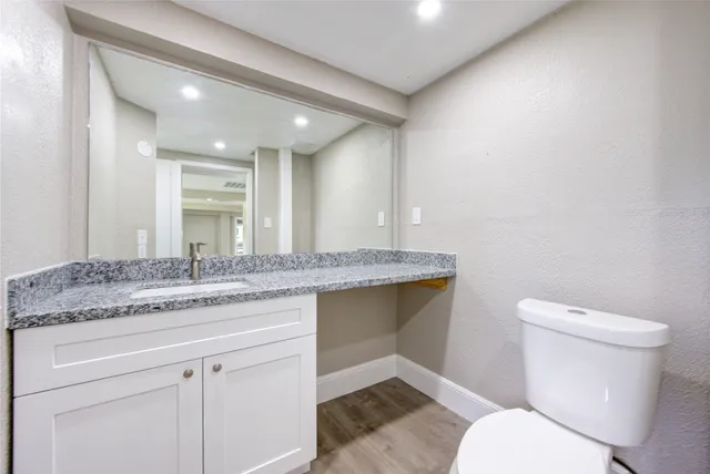 a bathroom with a granite countertop toilet sink and mirror