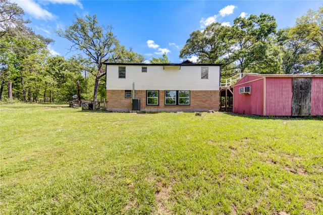 a view of a house with a yard and a large tree
