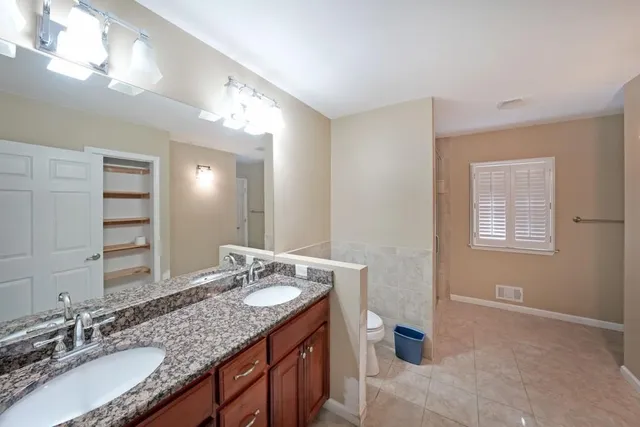 a bathroom with a granite countertop double vanity sink and a mirror