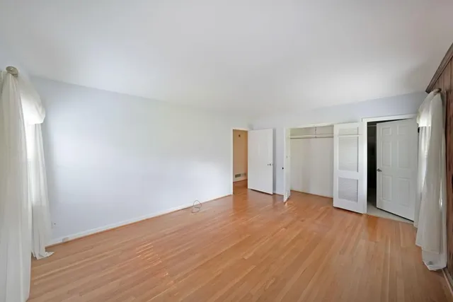 a view of an empty room with wooden floor and closet