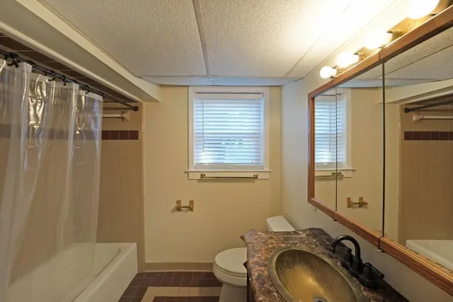 a bathroom with a granite countertop toilet sink and mirror