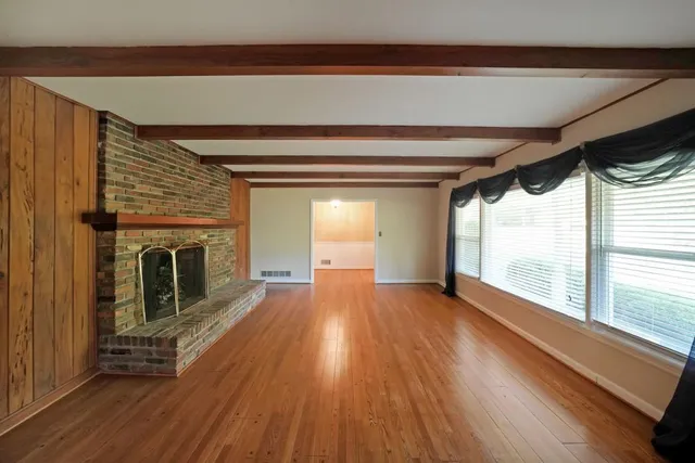 a view of a room with wooden floor a fireplace and windows