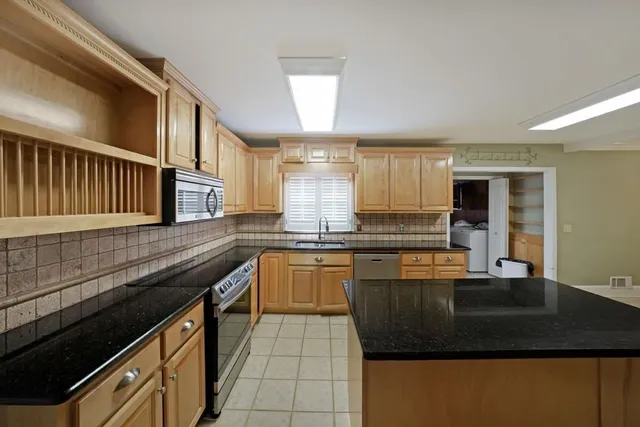 a kitchen with granite countertop a sink a stove top oven and cabinets