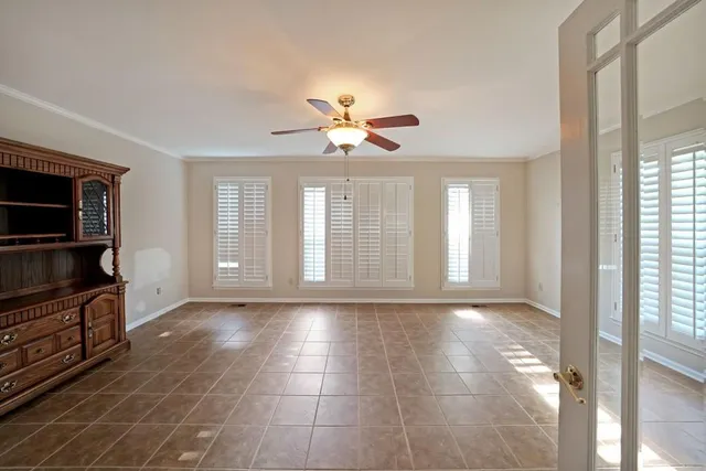 a view of n empty room with a window and a kitchen