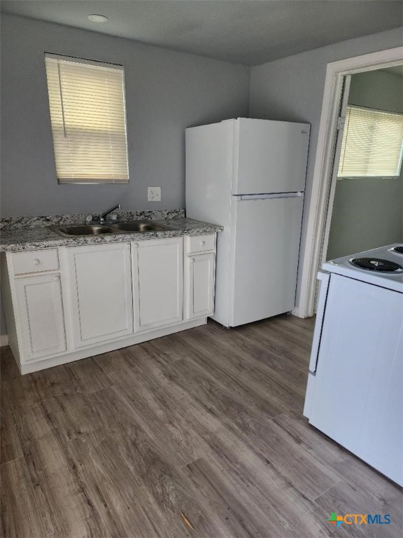 1309 South 3rd Street, Unit B Temple, TX 76504 - Photo 2 of 6 a kitchen with granite countertop a refrigerator a sink and white cabinets