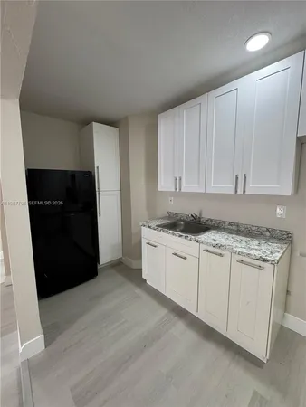 a kitchen with granite countertop white cabinets and refrigerator