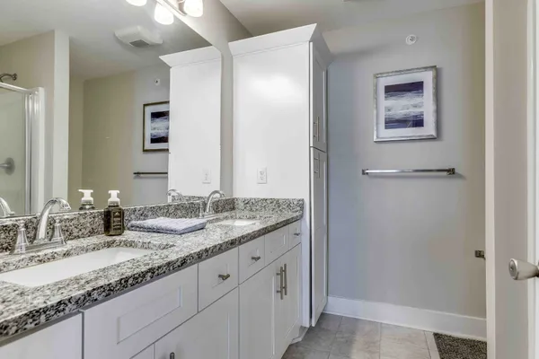 a bathroom with a granite countertop double vanity sink and two mirror
