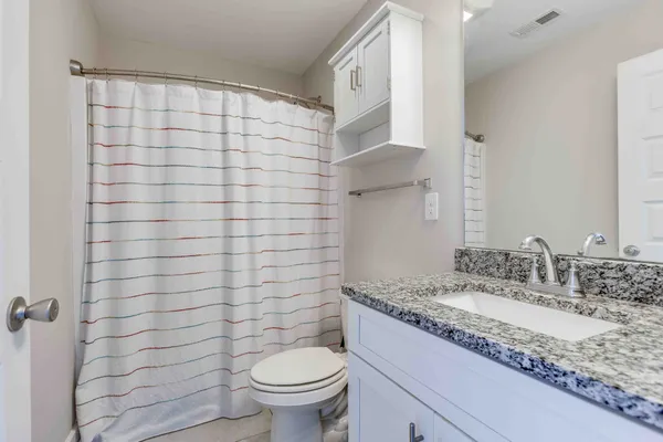 a bathroom with a granite countertop sink a toilet and shower