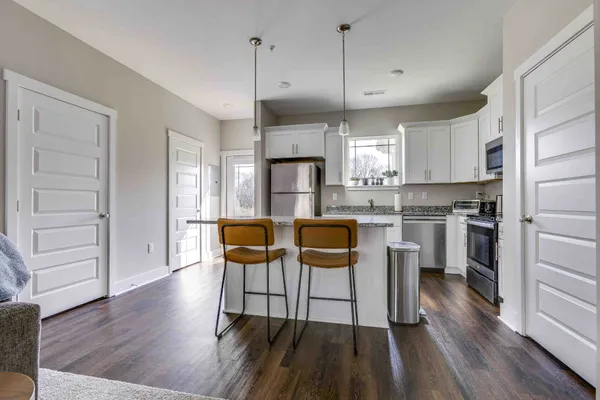 a kitchen with kitchen island granite countertop a sink a counter space appliances and cabinets