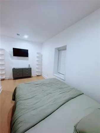 a spacious bedroom with a bed and a flat screen tv