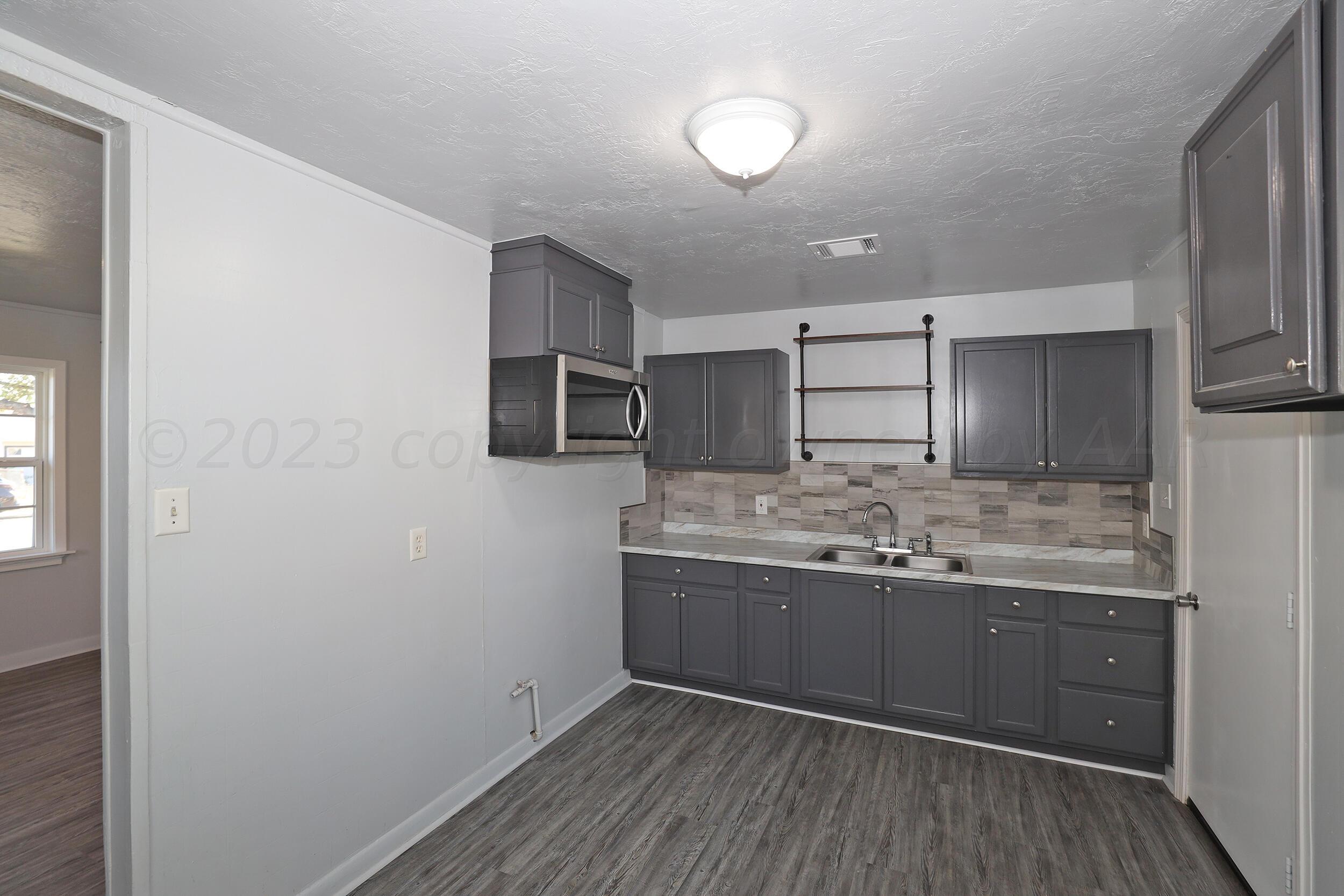 4614 South Travis Street Amarillo, TX 79110 - Photo 3 of 16 a kitchen with granite countertop a sink and cabinets