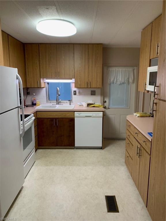 9322 Pitt Road Bonita Springs, FL 34135 - Photo 19 of 24 a kitchen with a sink a stove a refrigerator a center island and a cabinets