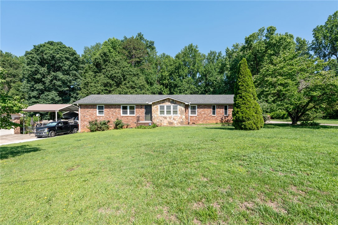 200 Echo Circle Easley, SC 29642 - Photo 5 of 35 A classic brick ranch home with a stone accent facade, surrounded by verdant trees and a well-kept lawn.