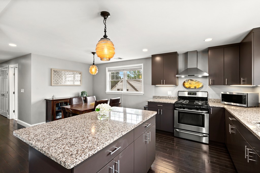 36 River Street, Unit 2 Arlington, MA 02474 - Photo 5 of 32 a kitchen with stainless steel appliances granite countertop a stove a sink a oven a dining table and chairs with wooden floor