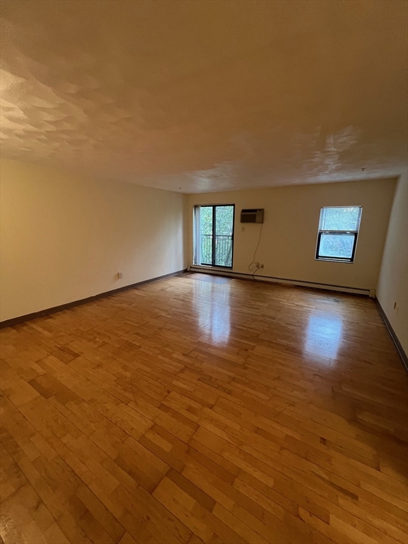 373 Highland Avenue, Unit 301 Somerville, MA 02144 - Photo 2 of 10 a view of an empty room with wooden floor and a window