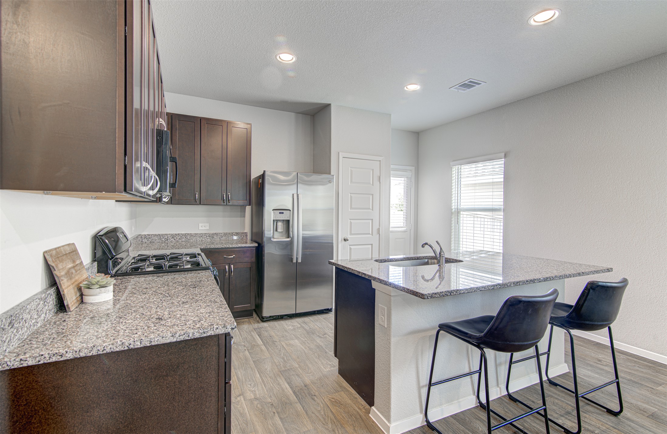 156 Tillage Road Elgin, TX 78621 - Photo 9 of 25 Granite counters and stainless steel appliances outfit this kitchen with an inviting island and sink.
