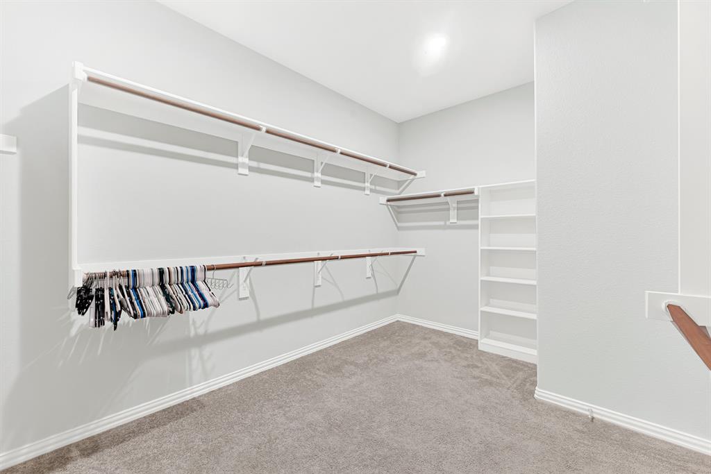 7640 Rhyner Way Fort Worth, TX 76137 - Photo 24 of 40 Spacious walk-in closet featuring extensive built-in shelving and hanging rods along multiple walls, neutral carpet flooring, recessed lighting, and ample storage capacity for a comprehensive wardrobe collection