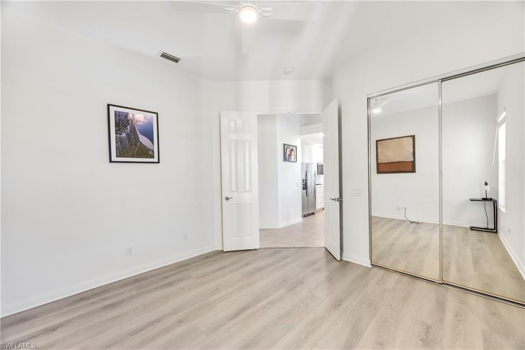 4708 Rio Poco Court Naples, FL 34109 - Photo 22 of 37 Unfurnished bedroom with light wood-style floors, a ceiling fan, stainless steel refrigerator with ice dispenser, and a closet