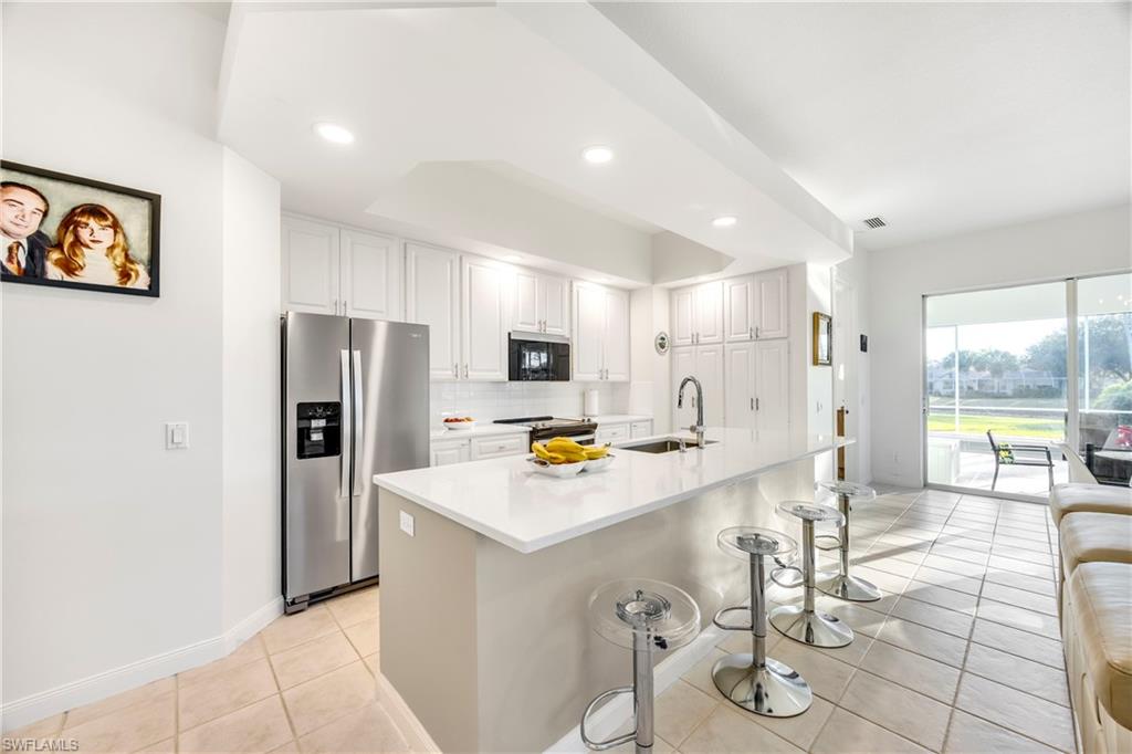 4708 Rio Poco Court Naples, FL 34109 - Photo 6 of 37 Kitchen with a breakfast bar, appliances with stainless steel finishes, a center island with sink, tasteful backsplash, and light tile patterned floors