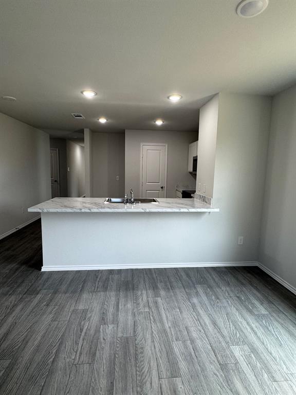 350 Azalea Trail Granbury, TX 76048 - Photo 6 of 18 a view of an empty room with wooden floor and kitchen