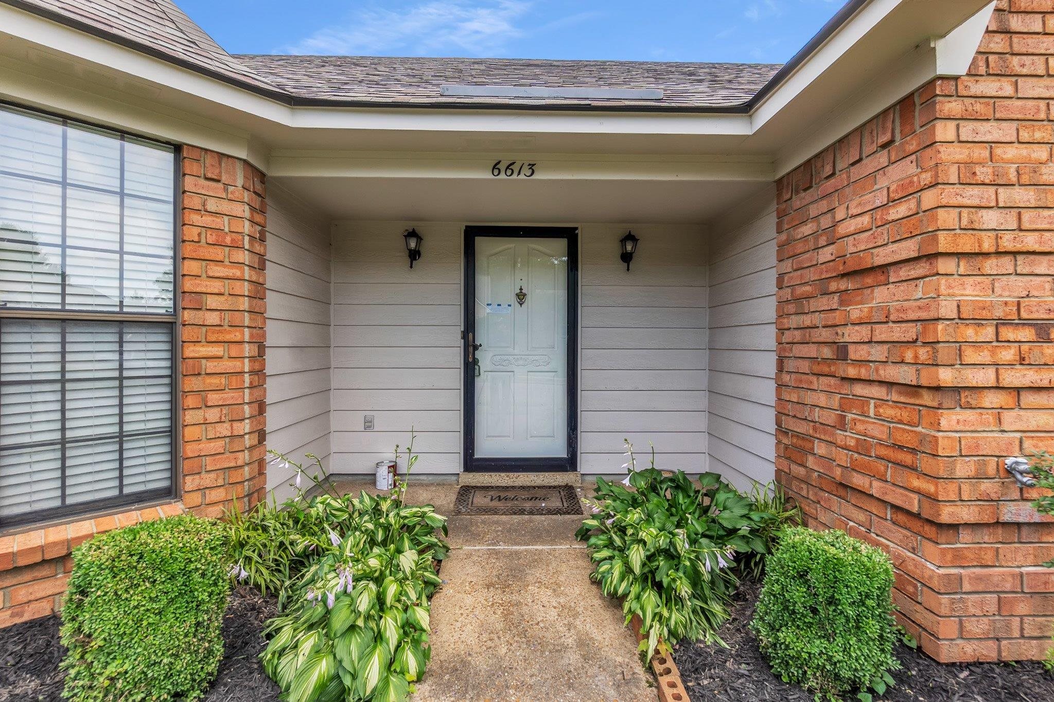6613 Stephan Ridge Drive Bartlett, TN 38135 - Photo 3 of 24 Inviting covered entryway featuring a white paneled door with dark trim, flanked by two outdoor sconces