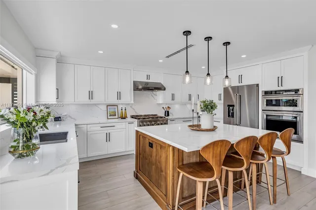 a kitchen with stainless steel appliances kitchen island granite countertop a table chairs sink and cabinets