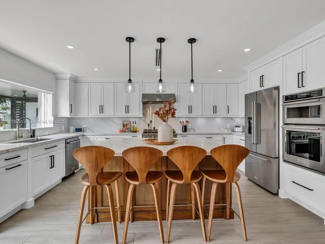a kitchen with kitchen island a stove a sink a counter top space and cabinets