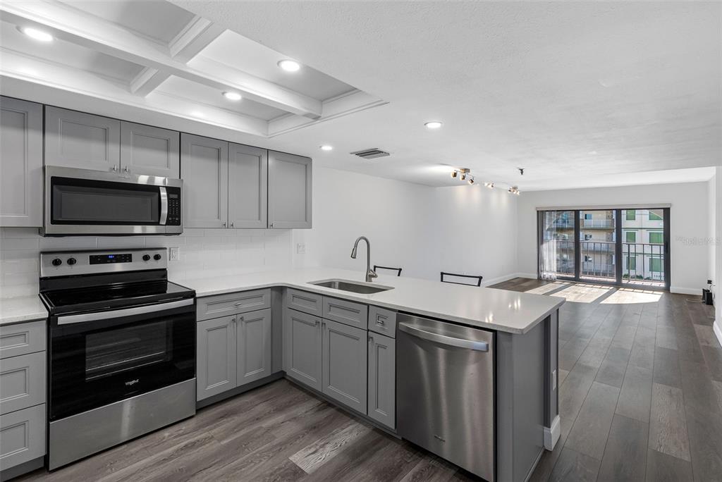 14001 Gulf Boulevard, Unit 404 Madeira Beach, FL 33708 - Photo 16 of 24 a kitchen with stainless steel appliances granite countertop a sink and stove top oven