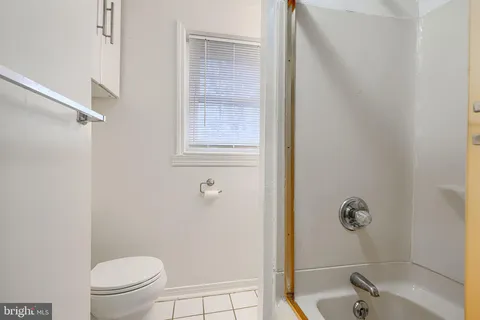 a bathroom with a granite countertop bathtub shower sink vanity and toilet
