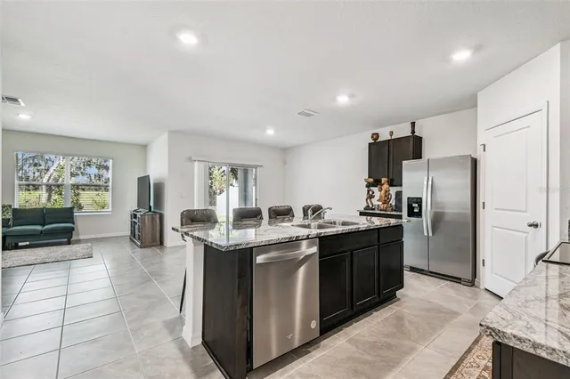 a kitchen with stainless steel appliances granite countertop a sink and a refrigerator