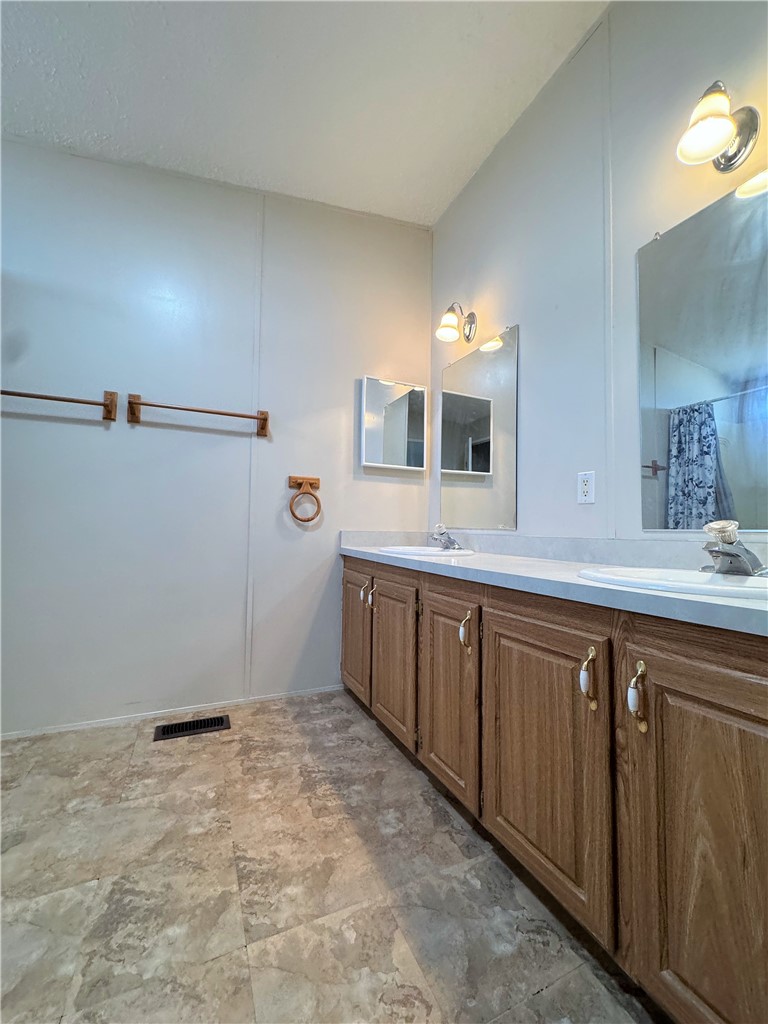 14224 East Randy Ranch Road Kingman, AZ 86401 - Photo 14 of 75 The bathroom features a double vanity with wood cabinetry, a light-colored countertop, and two framed mirrors