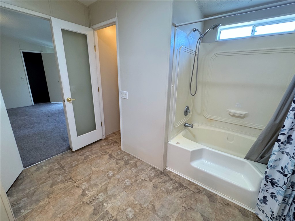14224 East Randy Ranch Road Kingman, AZ 86401 - Photo 16 of 75 The bathroom features a combination shower and bathtub unit, vinyl flooring, and a window providing natural light