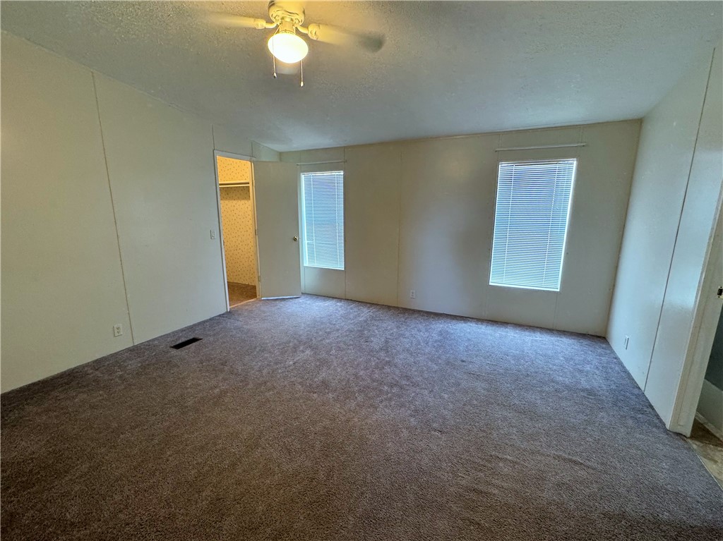14224 East Randy Ranch Road Kingman, AZ 86401 - Photo 19 of 75 Room featuring neutral tone carpet, two windows with blinds, a ceiling fan with light, and a closet with a hanging rail