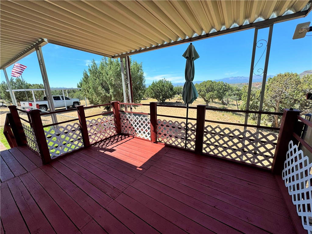 14224 East Randy Ranch Road Kingman, AZ 86401 - Photo 32 of 75 The property features a spacious red-painted deck with white lattice railing, offering expansive views of the surrounding landscape and distant mountains