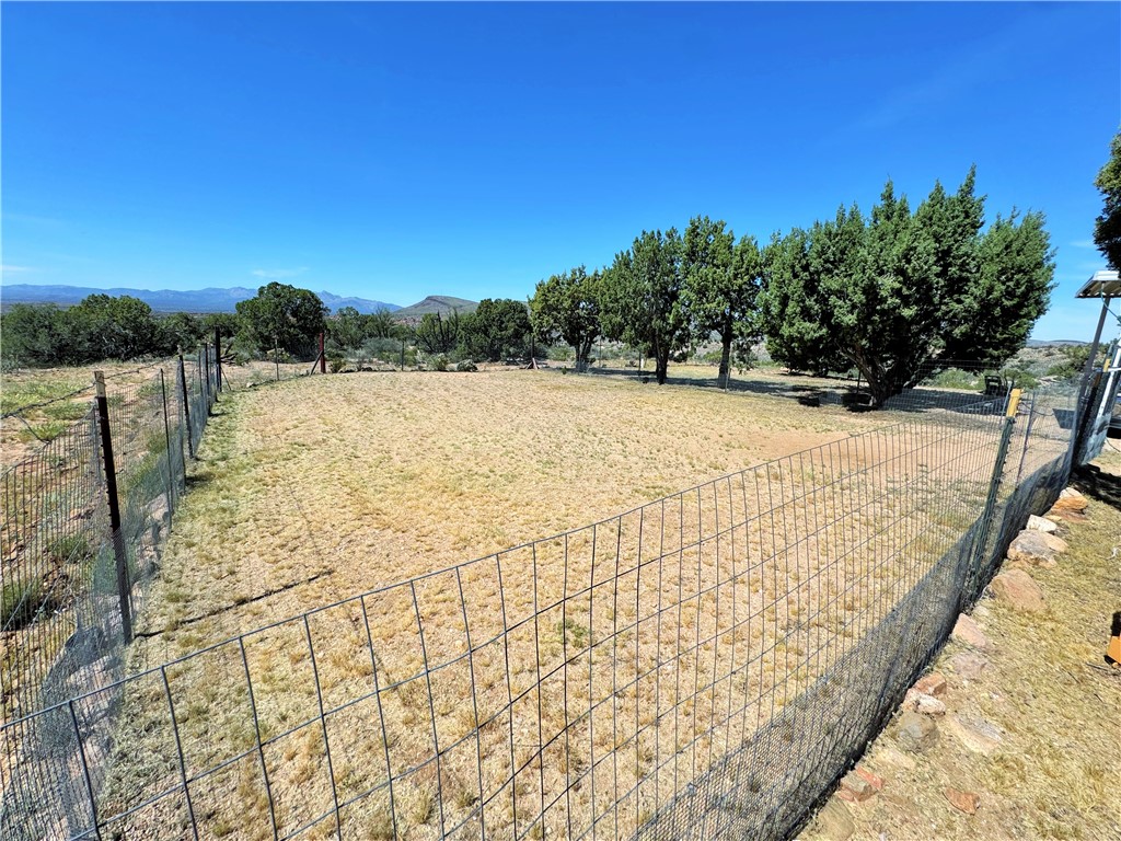14224 East Randy Ranch Road Kingman, AZ 86401 - Photo 39 of 75 The property features a fenced yard with mature trees and views of distant mountains under a clear sky