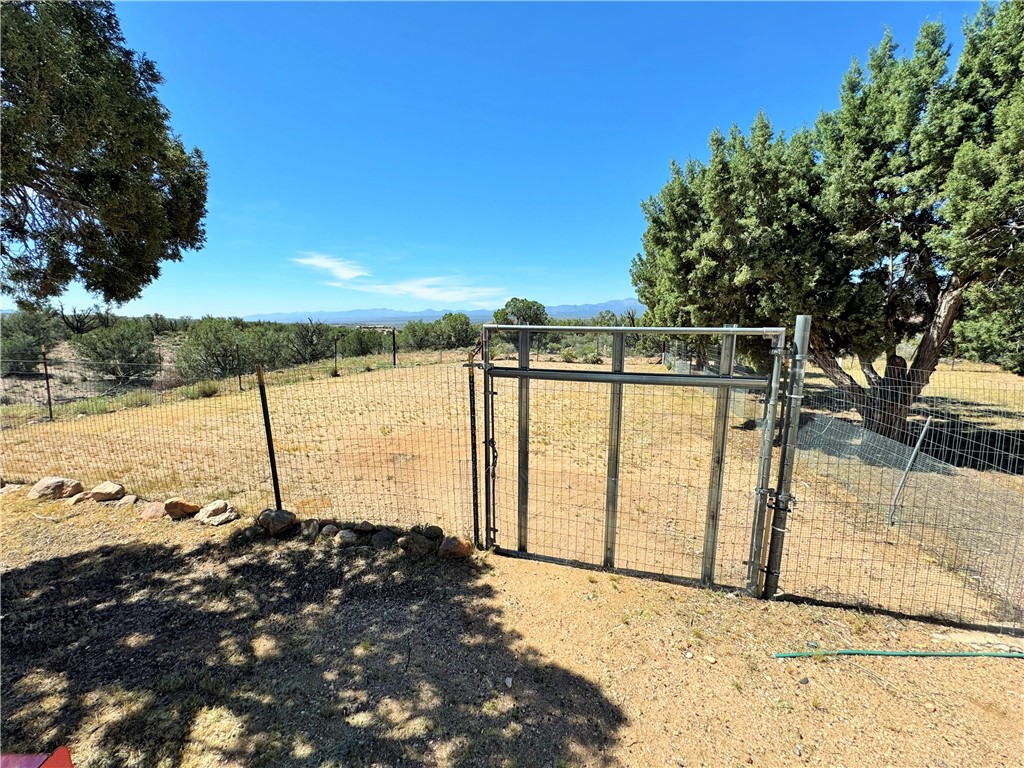14224 East Randy Ranch Road Kingman, AZ 86401 - Photo 40 of 75 The property features a fenced perimeter with a metal gate and includes mature trees within the lot