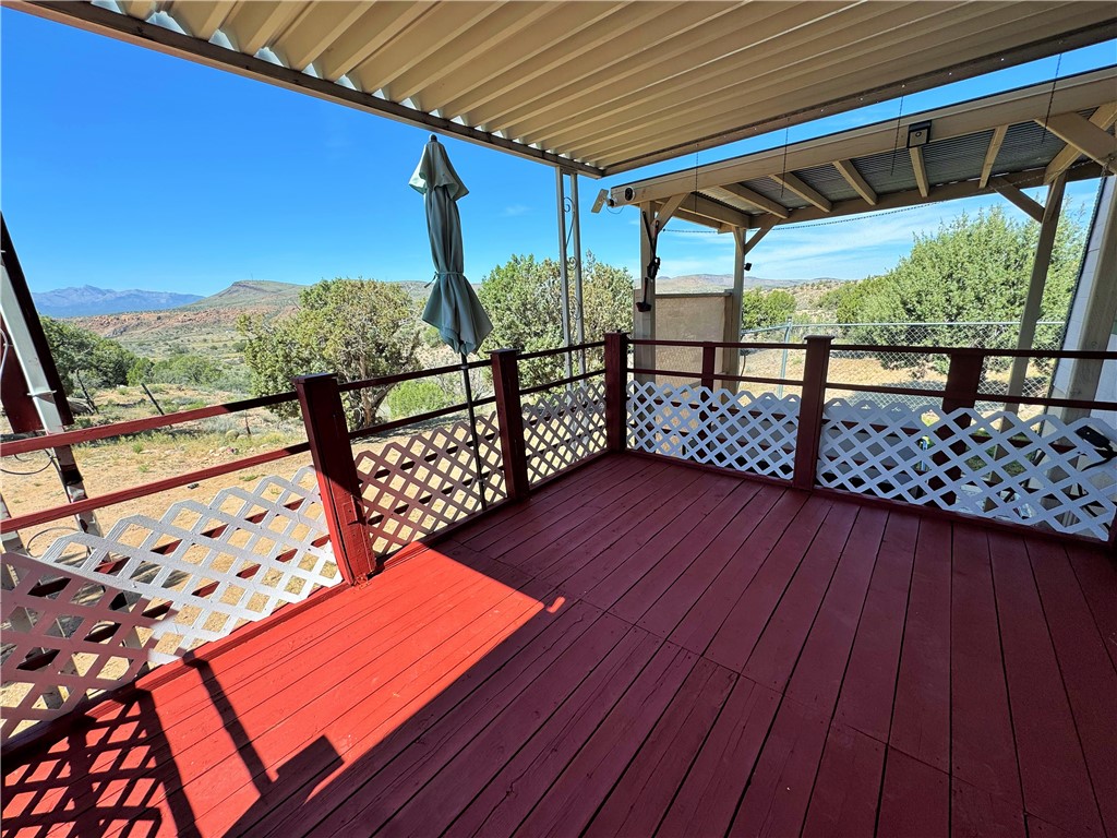 14224 East Randy Ranch Road Kingman, AZ 86401 - Photo 4 of 75 This property features a covered outdoor deck with a red-painted floor, white lattice railing, and scenic views of the surrounding landscape and distant mountains