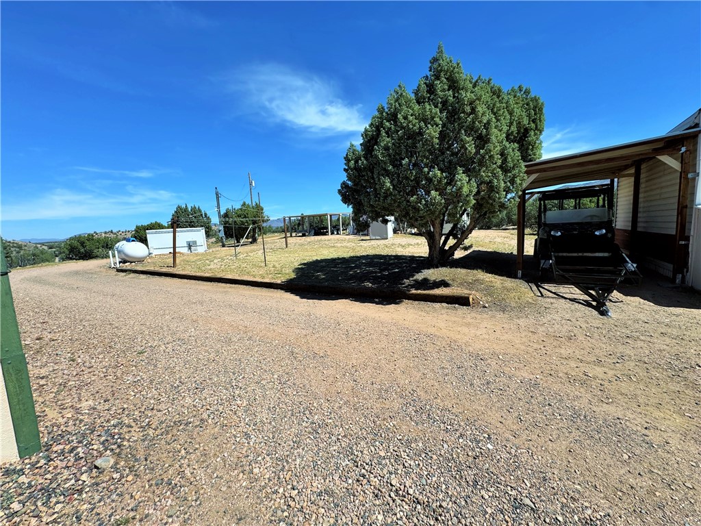 14224 East Randy Ranch Road Kingman, AZ 86401 - Photo 41 of 75 The property features a spacious gravel driveway, mature trees, and a covered carport