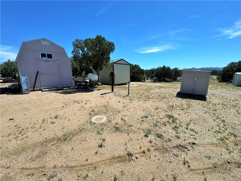 14224 East Randy Ranch Road Kingman, AZ 86401 - Photo 50 of 75 The property features a spacious outdoor area with two storage sheds and a clear blue sky overhead