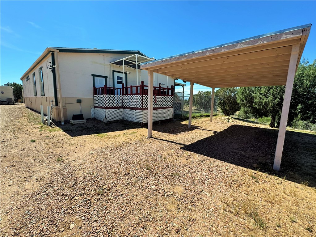14224 East Randy Ranch Road Kingman, AZ 86401 - Photo 7 of 75 Property exterior with a covered deck, white lattice skirting, and a covered carport with a light wood underside