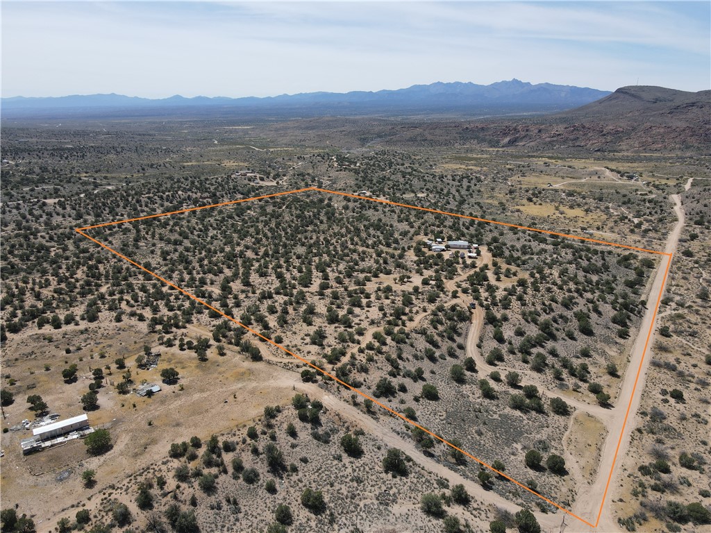 14224 East Randy Ranch Road Kingman, AZ 86401 - Photo 73 of 75 Expansive property with a diverse landscape featuring scattered trees and visible dirt roads, all set against a backdrop of distant mountains