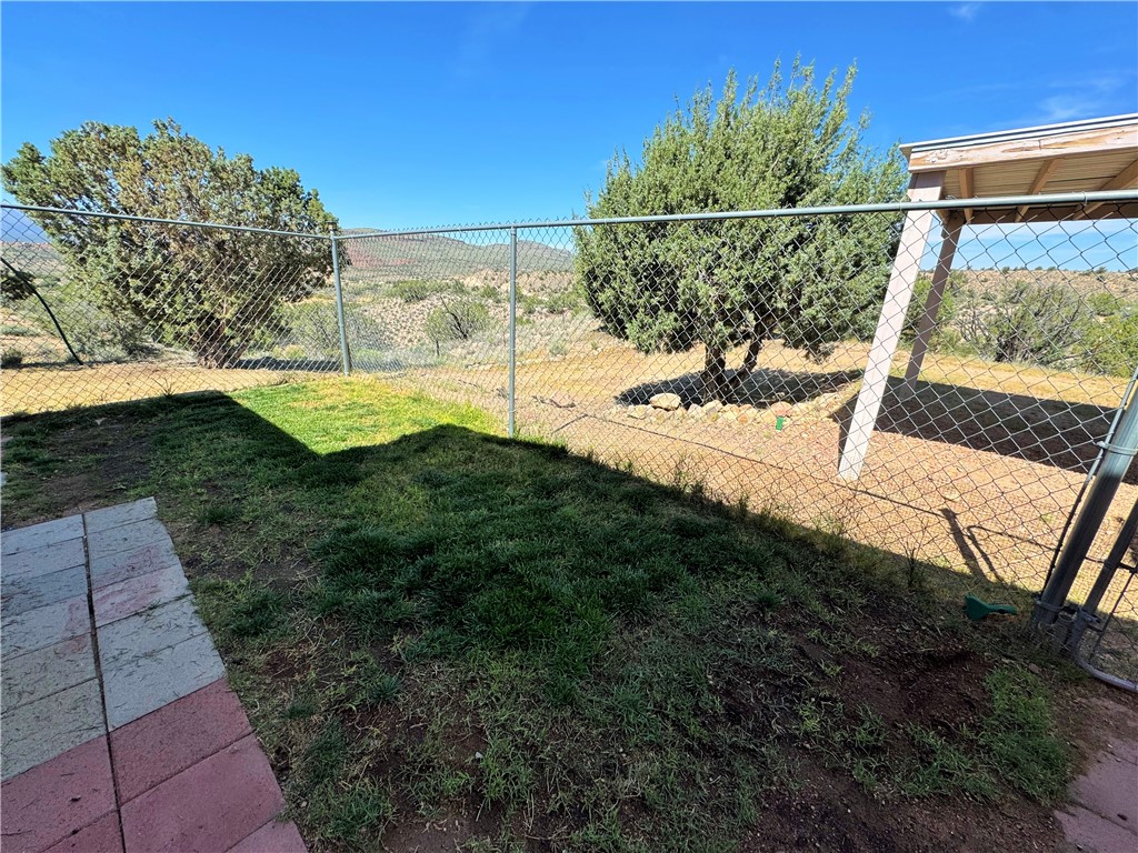 14224 East Randy Ranch Road Kingman, AZ 86401 - Photo 8 of 75 The property features a fenced yard with a combination of grass and natural landscaping, complete with mature trees