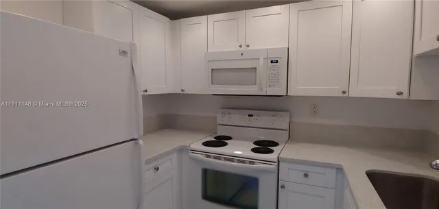 a kitchen with white cabinets and white appliances