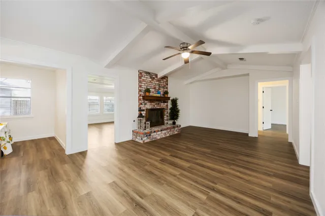 an empty room with wooden floor ceiling fan and windows