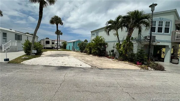 a view of a house with a yard and palm trees