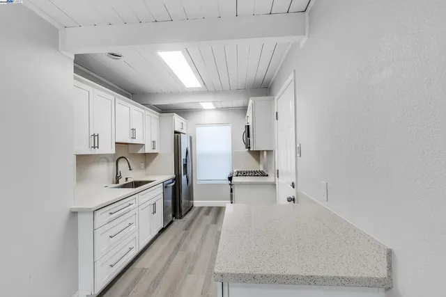 a large kitchen with a stove a sink dishwasher and a refrigerator with wooden floor