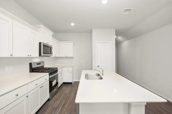 a kitchen with a sink wooden floor and stainless steel appliances