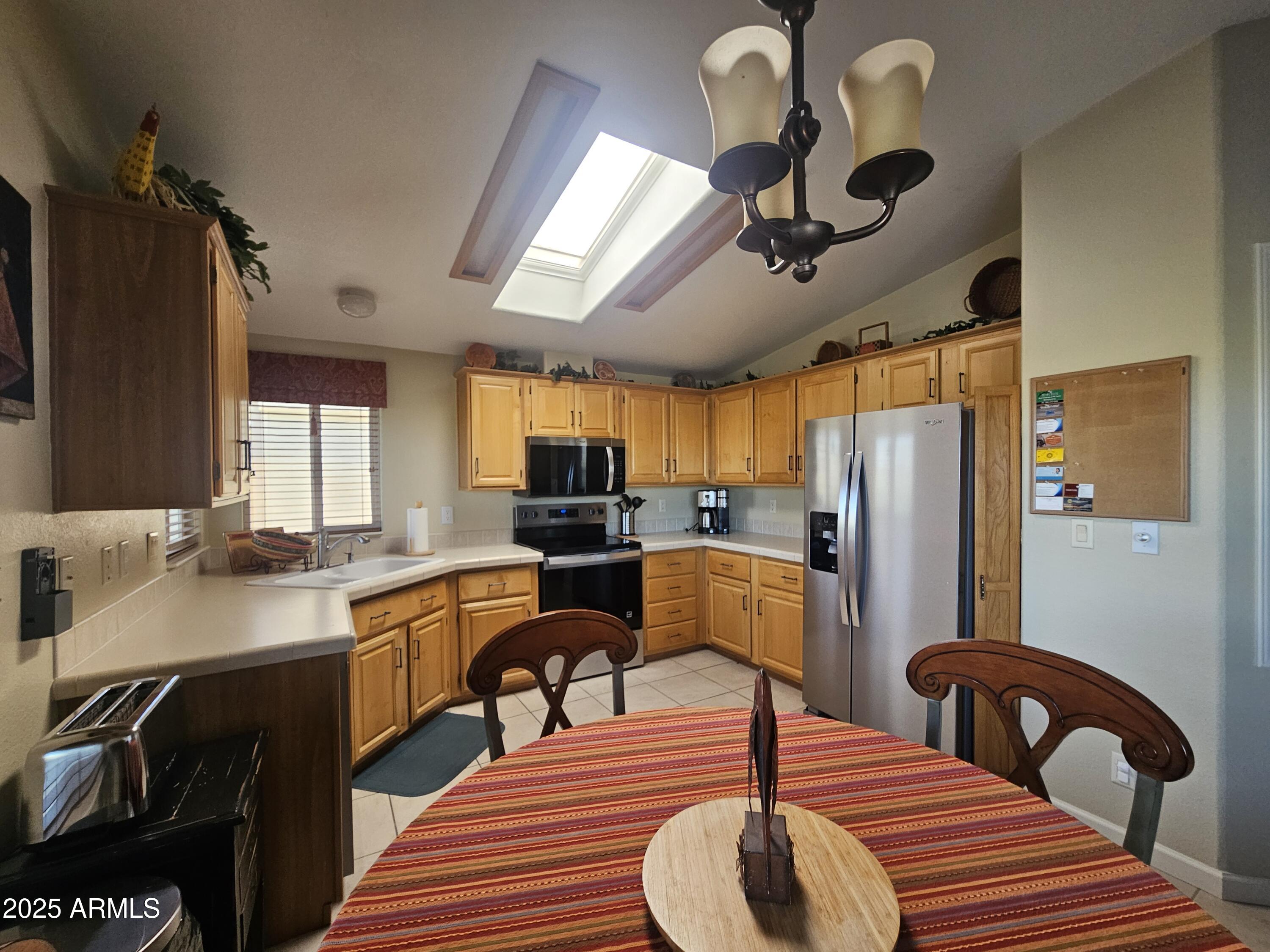 650 North Hawes Road, Unit 4820 Mesa, AZ 85207 - Photo 8 of 54 a kitchen with sink refrigerator dining table and chairs